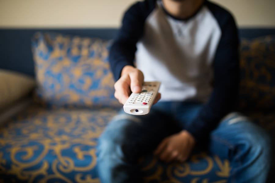 Menino com um controle na mão assistindo TV