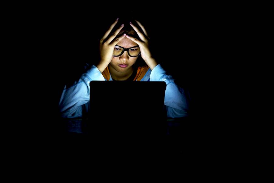 Moça jovem e depressiva assistindo séries no notebook